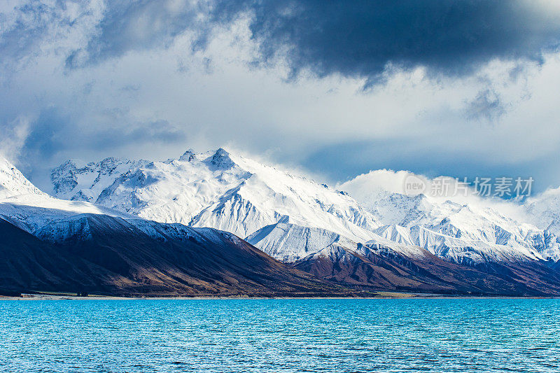 绿松石湖与戏剧性的景观雪山的背景