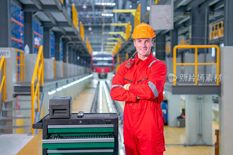 在电气或空铁工厂的工作场所，专业技术工人双臂交叉站着微笑着看着相机的肖像。