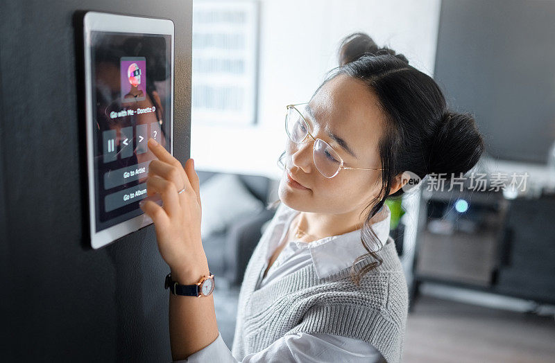 音乐、平板电脑和亚洲女性在家里、公寓和客厅都有数字系统。技术，未来的设计和女孩打字歌曲，人工智能软件的轨道和音频，生物识别和用户界面