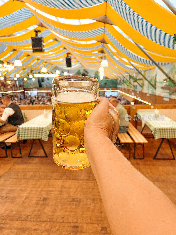 在慕尼黑啤酒馆举行的秋季庆祝活动中，手持啤酒杯的群众