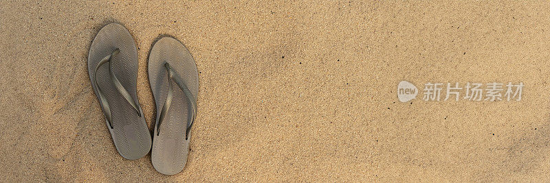 沙滩上的浅色凉鞋或人字拖横幅。金色的沙子。放文字的地方。前视图。夏季和海上度假的概念
