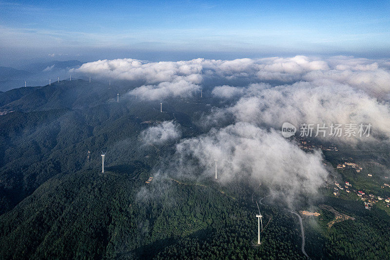 一组风力涡轮机在被雾覆盖的山顶上