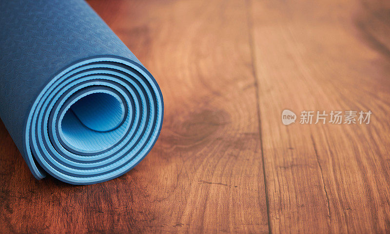 在有文字空间的木地板上卷起蓝色瑜伽垫