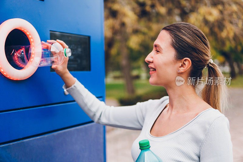 年轻女子在机器里回收塑料瓶