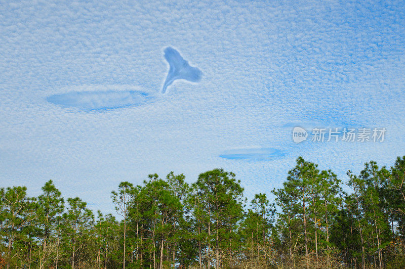 天使或耶稣望着鲭鱼般的天空，云层由成排的卷积云或高积云组成，呈现出波浪起伏的图案，外观类似鱼鳞树线