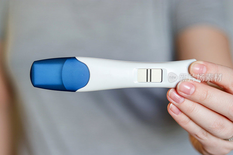 一名妇女拿着数字妊娠测试阳性的特写