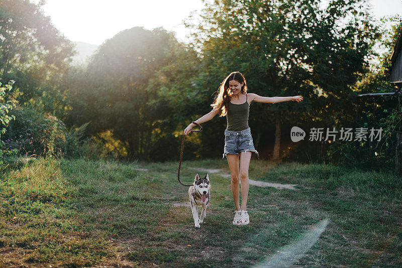 秋天黄昏时分，一位妇女牵着一只狗在森林里散步。与你心爱的狗一起进行生活方式运动训练