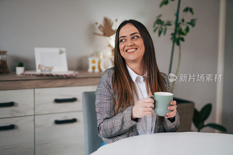 漂亮的女商人在家里的客厅里喝咖啡