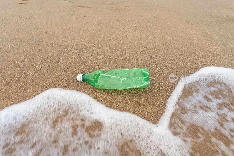 人类废物处理造成的海滩上的塑料瓶污染表明海岸清理和保护的必要性。环境问题源于废物的管理和处置。