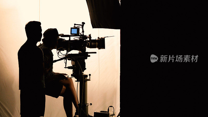 在大型摄影棚中使用专业设备，如带有监视器和三脚架或万向架的高清4k摄像机，拍摄剪影或录制电视电影广告的幕后视频制作。