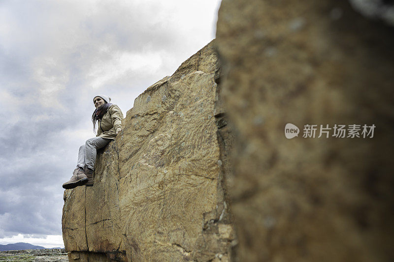 女人坐在悬崖上。回归自然的独自旅行。