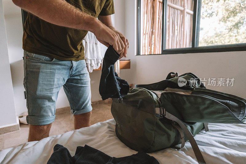 男旅行者打包旅行的细节，把衣服放在行李袋里