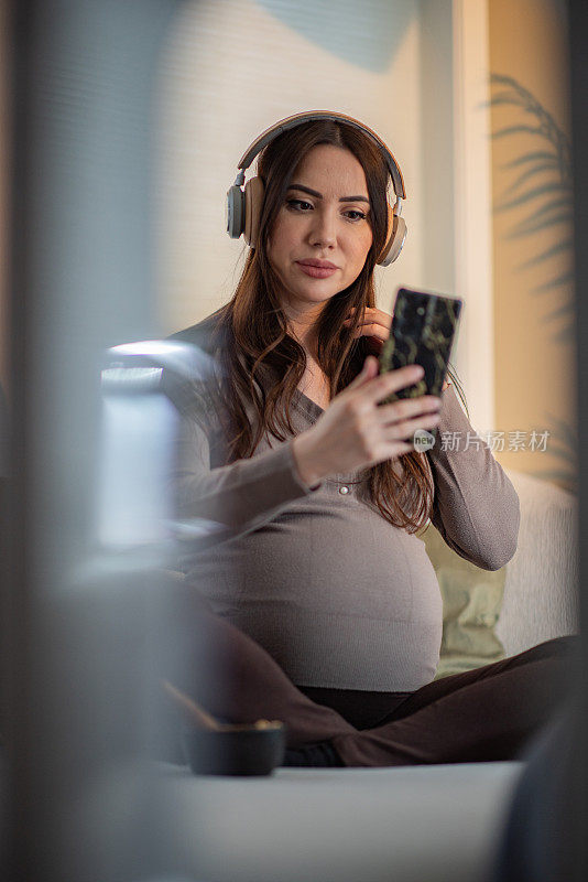 孕妇在家戴着耳机听音乐
