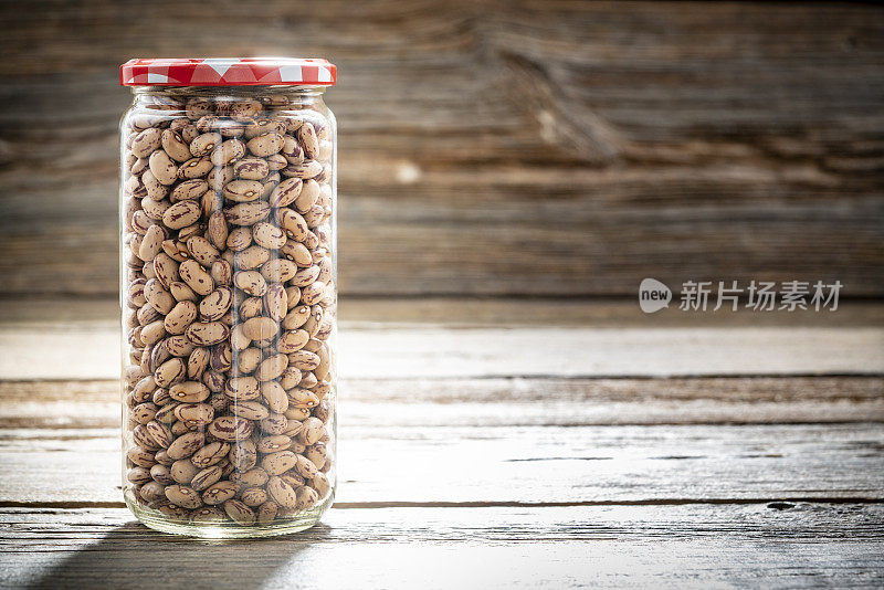 干燥的斑豆豆类在一个玻璃罐特写孤立在乡村木材