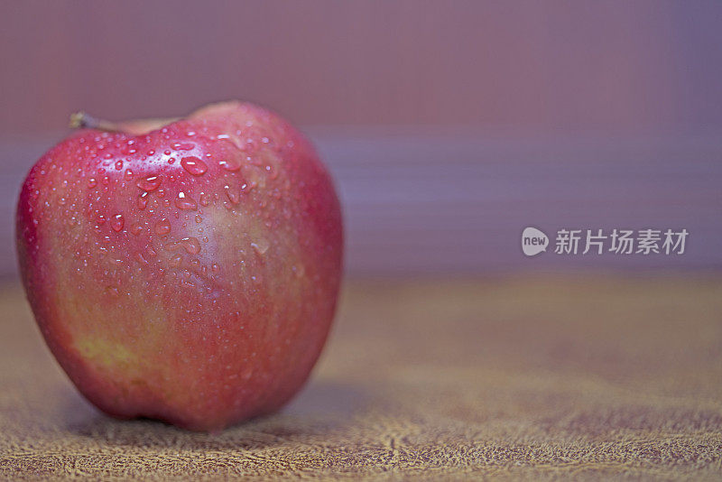 红苹果在紫光棕色皮革背景