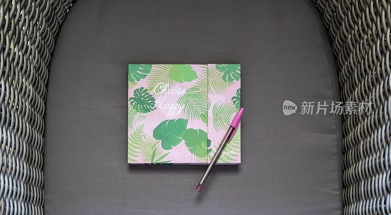 粉红色的铅笔，绿色的叶子印在日记本上