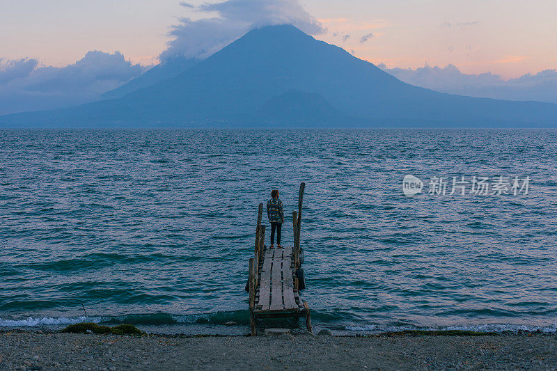 日落时分，一名男子站在危地马拉阿提特兰湖的码头上