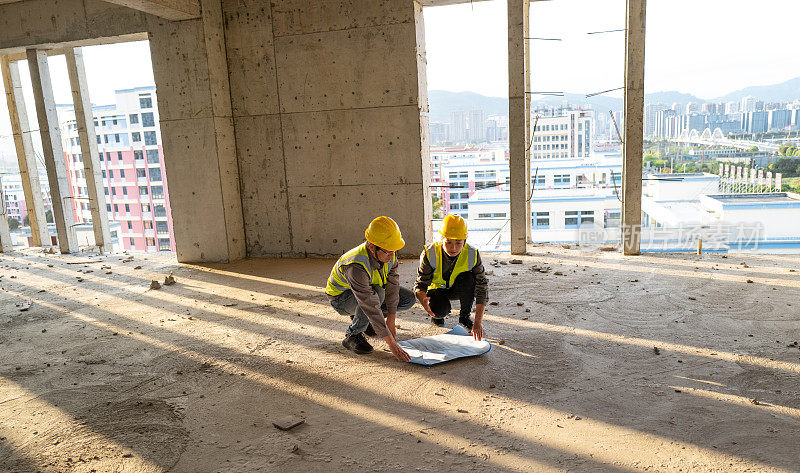 男工程师和女工程师在混凝土建筑工地看蓝图