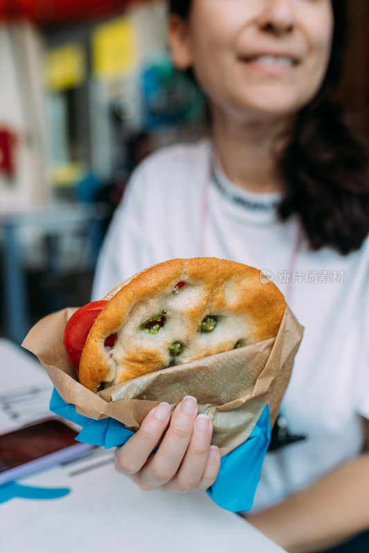 吃佛卡夏三明治加香蒜沙司和番茄的女人