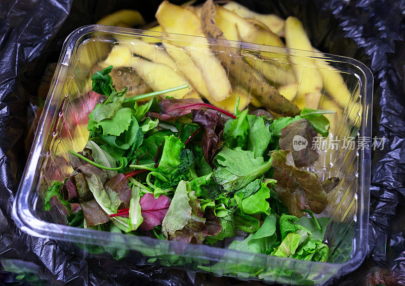 垃圾土豆和莴苣叶在垃圾袋。家里的食物浪费。