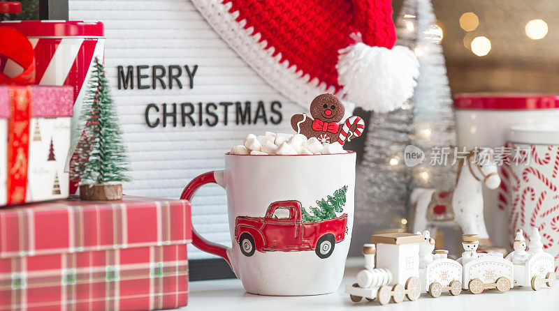 一个标牌上写着圣诞快乐，礼物，圣诞老人帽子，一杯热可可，棉花糖和姜饼人的背景是一个美丽的bokeh。温馨的新年和寒假概念
