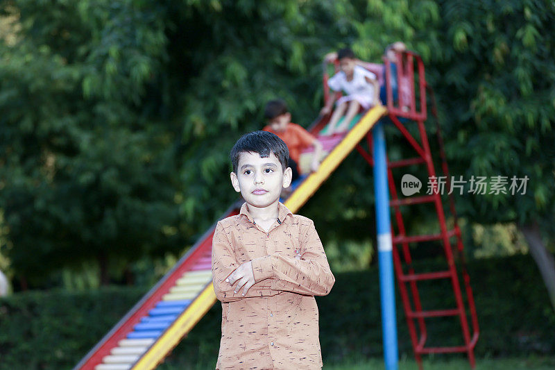 学校放假期间，孩子站在公园的滑梯旁