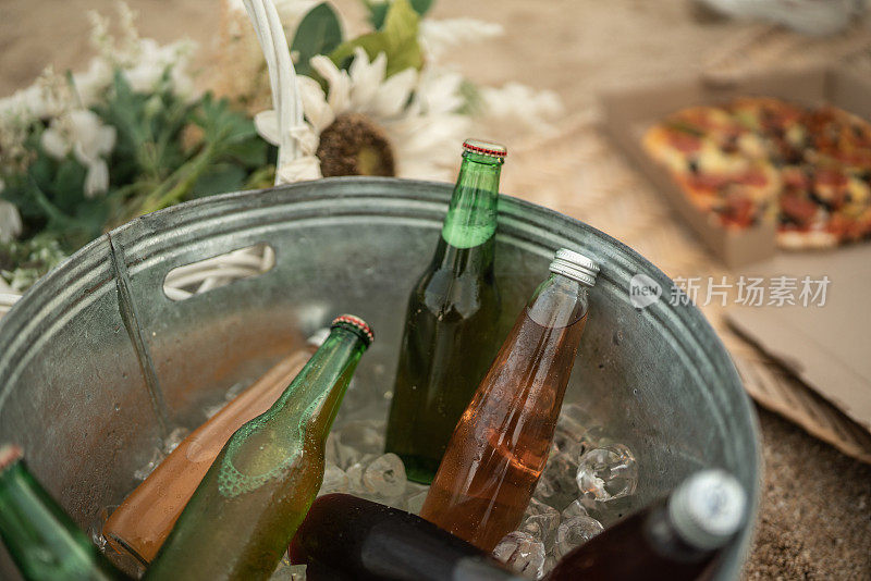 在海滩的社交聚会上，冰桶里装着啤酒和苏打水瓶