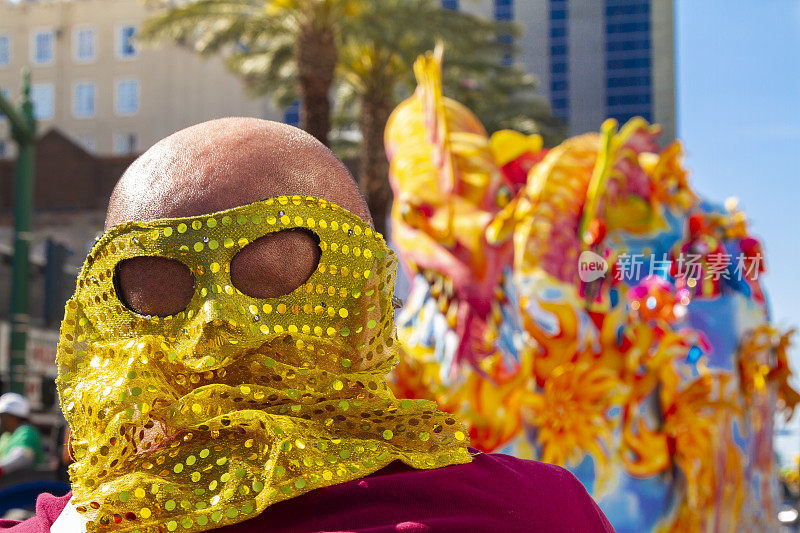 美国路易斯安那州新奥尔良市，一名戴着面具的男性游客在狂欢节庆祝活动中穿过运河街