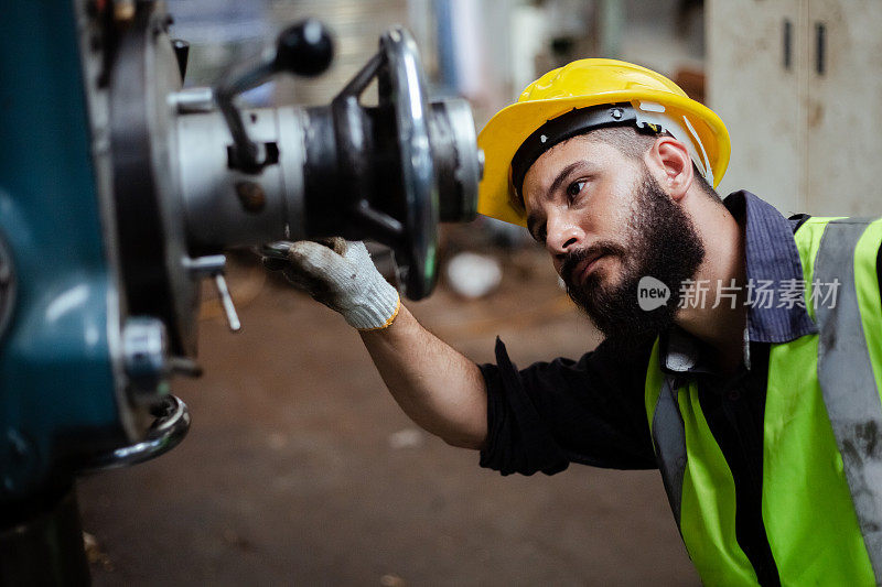 在工业车间工作的男工程师戴着黄色头盔制服。帅气的工人，脸上留着胡子。副本的空间。