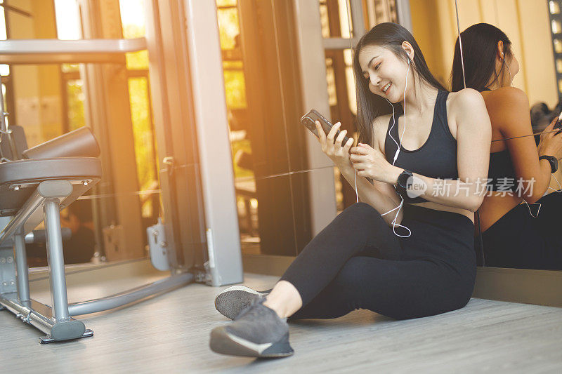 亚洲女性玩手机玩社交媒体。在健身房。