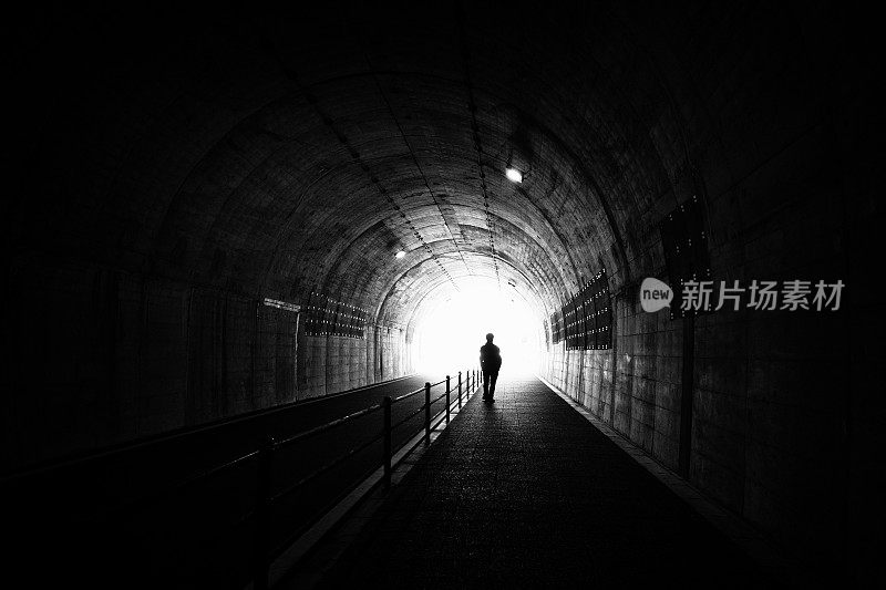 一个人穿过黑暗的隧道走向出口的剪影