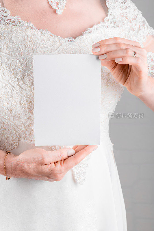 身穿婚纱的女子手持白色背景5x7的婚礼舞台邀请卡模型