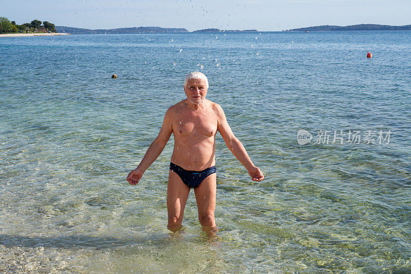 老年男子一个帕金森病患者在海水里玩水。