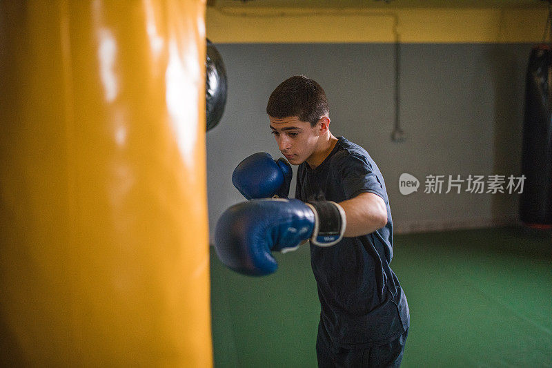 男性自由搏击运动员在拳击馆训练，专注于变得更强壮