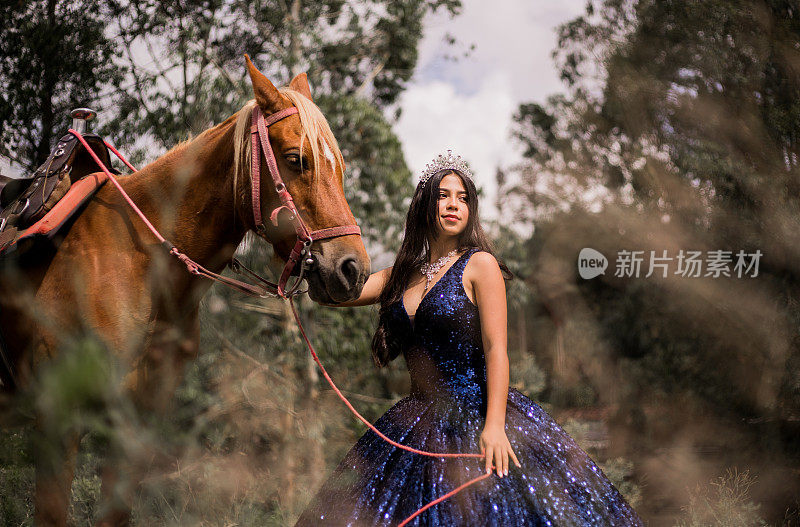 一个女人的肖像在quinceañera裙子与她的马在她的身边，因为她把它在她的手中