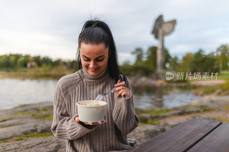 美丽的年轻女子在湖边吃午餐