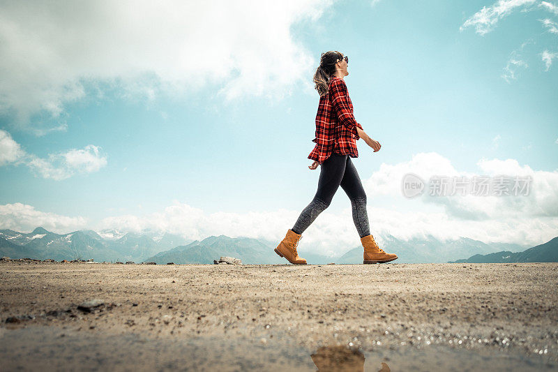 一个女人走在高山上，只有云在背后。