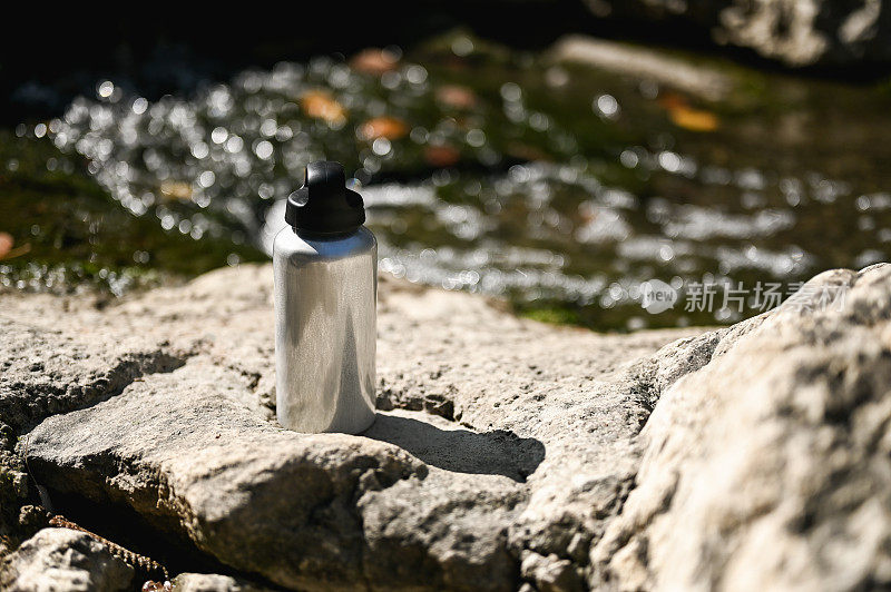 铝水瓶在河边的石头。