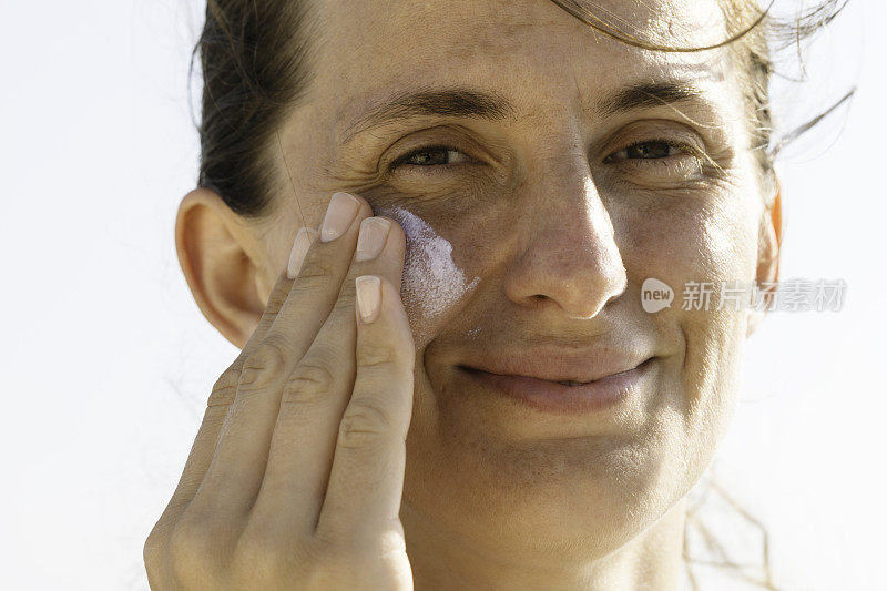 女人在脸上涂防晒霜