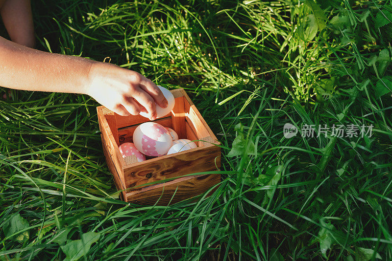 一个孩子的手把找到的复活节彩蛋放进盒子里的特写