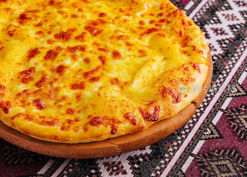 美味的奶酪披萨放在传统的桌布上