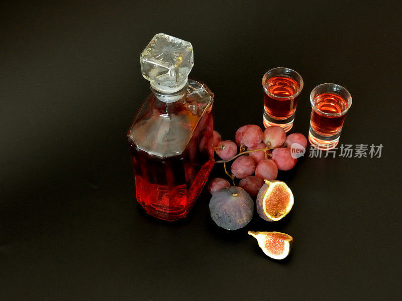 葡萄无花果利口酒，两杯一瓶，黑色背景的成熟水果。