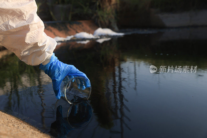 特写科学家手与白色PPE服和丁腈手套收集样品废水进入烧瓶实验室水分析，工业和环境的概念