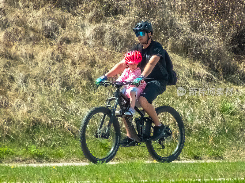 一个人在春天带着孩子骑自行车。