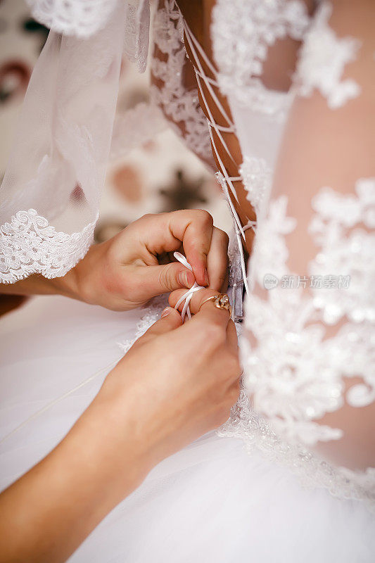 伴娘帮助新娘穿上婚纱。