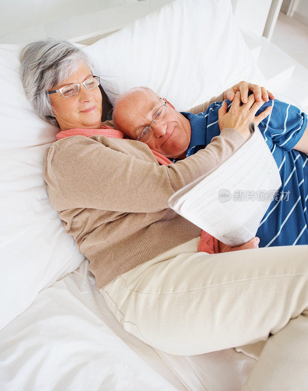一对相爱的老男女躺在床上看报纸