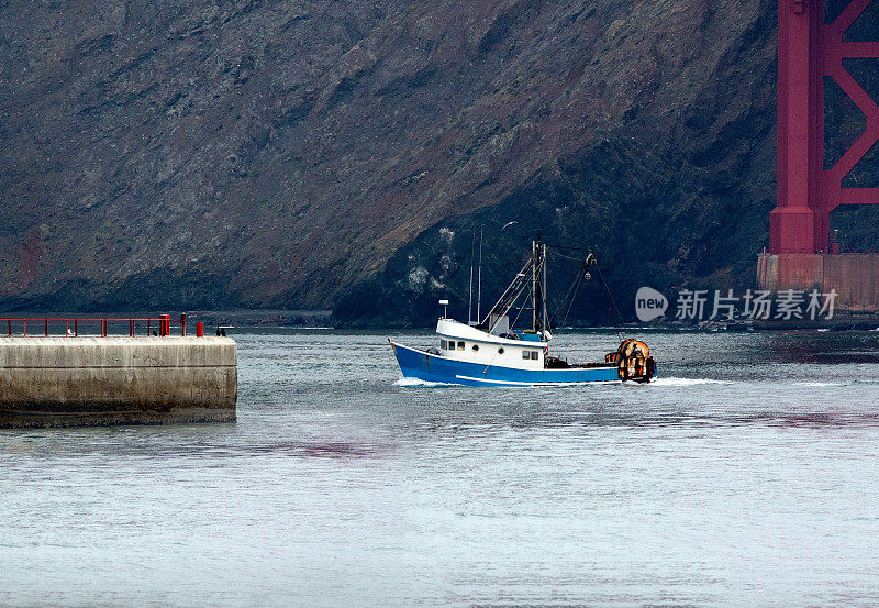 一艘渔船经过金门大桥驶向大海