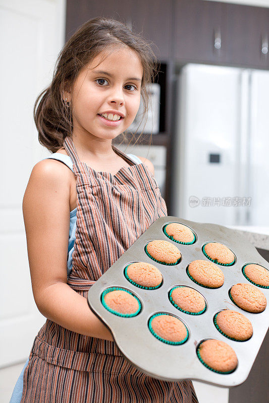 小女孩在烤杯子蛋糕