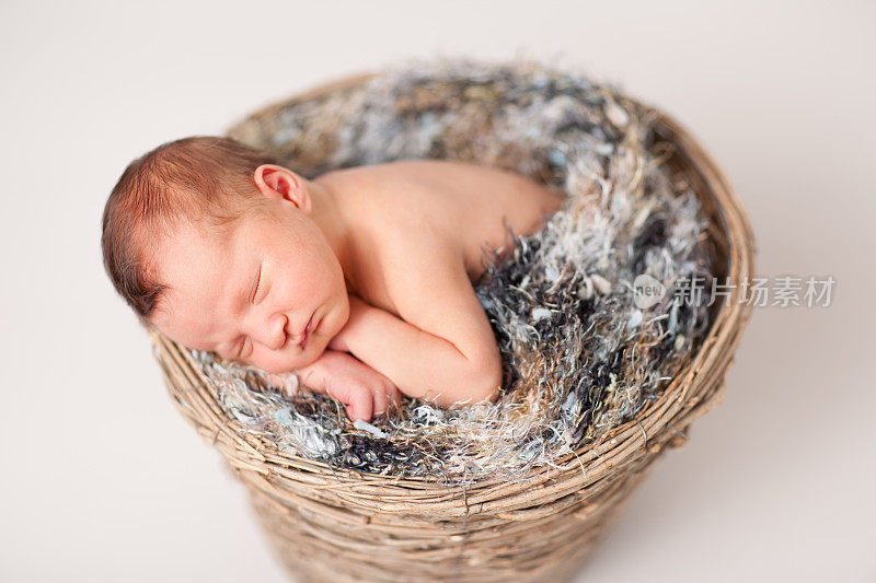 刚出生的婴儿睡在毛茸茸的毯子的篮子里