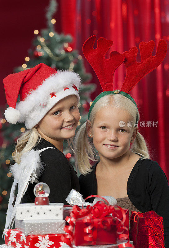 快乐的女孩戴着圣诞帽和鹿角与圣诞礼物